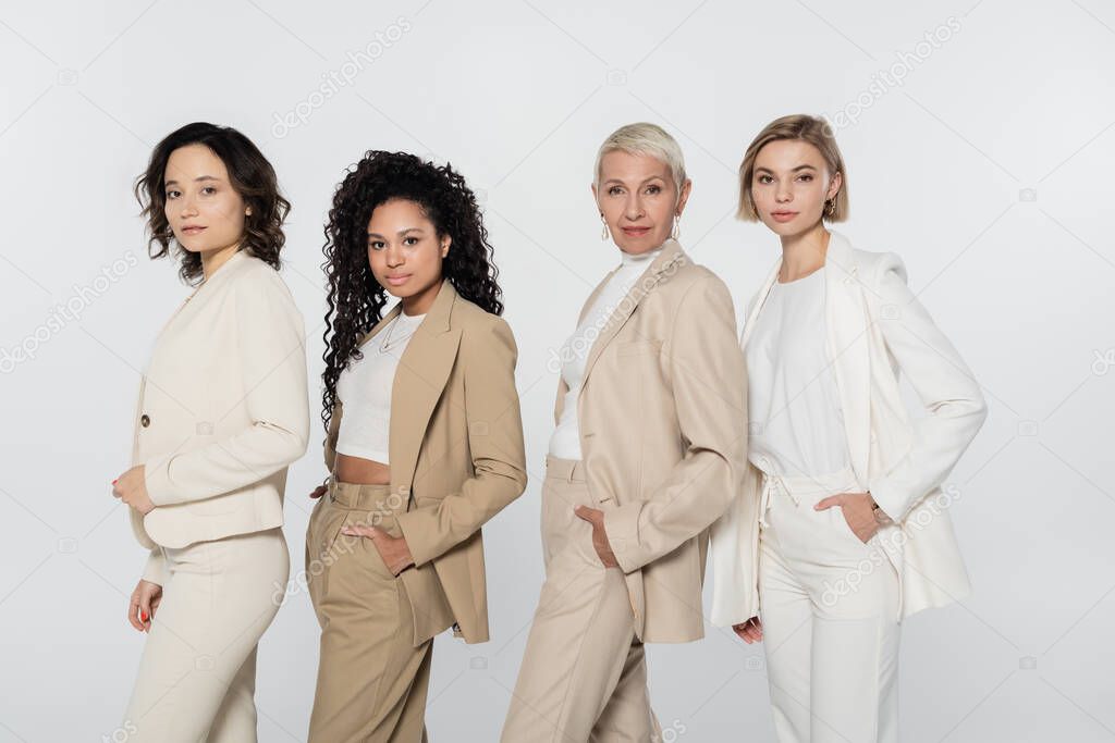 Multiethnic businesswomen in formal wear posing isolated on grey, feminism concept