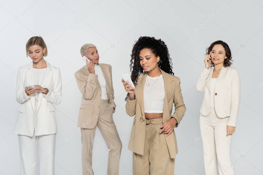 African american businesswoman using smartphone near colleagues isolated on grey 