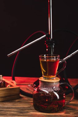 Çaydanlıkta çay, nargile yakınında, tahtadan yüzey, siyah üzerine izole edilmiş.