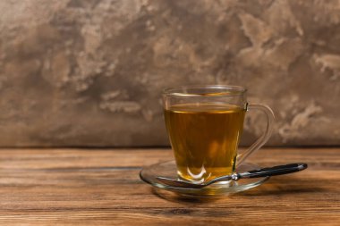 Çay fincanı çay fincanında ve kaşık ahşap yüzeyde dokulu taş arka planda. 