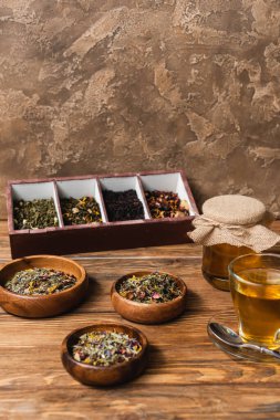 Kuru çay, fincan ve kavanoz bal ile ahşap yüzeyde dokulu taş arka planda 