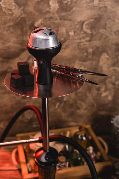 Coals and tweezers on hookah on textured stone background 