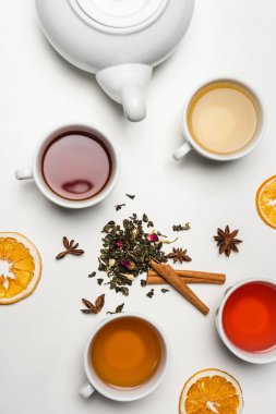 Beyaz arkaplanda çay fincanları ve çaydanlık yakınlarındaki kuru baharatların üst görünümü 