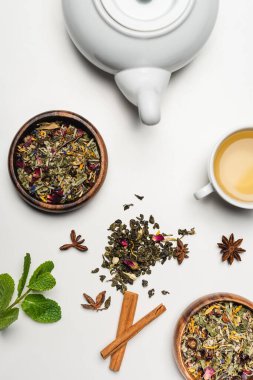 Beyaz arka planda kuru çay, çaydanlık ve baharatların üst görüntüsü 