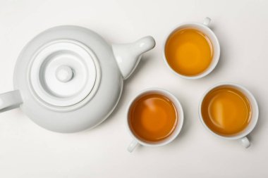 Çay fincanlarının beyaz arkaplanda çaydanlık yakınında üst görünümü 