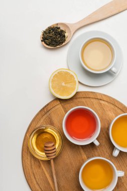 Beyaz arka planda bal ve limonun yanındaki çay fincanlarının üst görüntüsü 