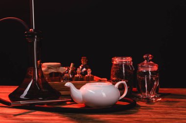 Çaydanlığın yanında nargile ve siyah üzerine izole edilmiş tahta yüzey kavanozları. 