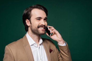 Bıyıklı mutlu genç adam telefonda koyu yeşille konuşuyor. 