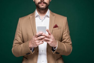 Bıyıklı genç adam koyu yeşil üzerinde akıllı telefon kullanıyor. 