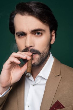 Koyu yeşil üzerinde gülümseyen bıyıklı bir adamın portresi 