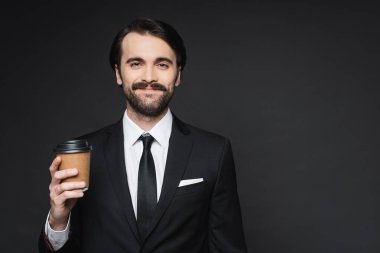 Bıyıklı neşeli iş adamı elinde kağıt bardakla koyu gri