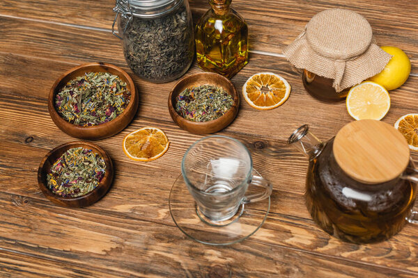 Cup near tea, honey and bowls on wooden surface