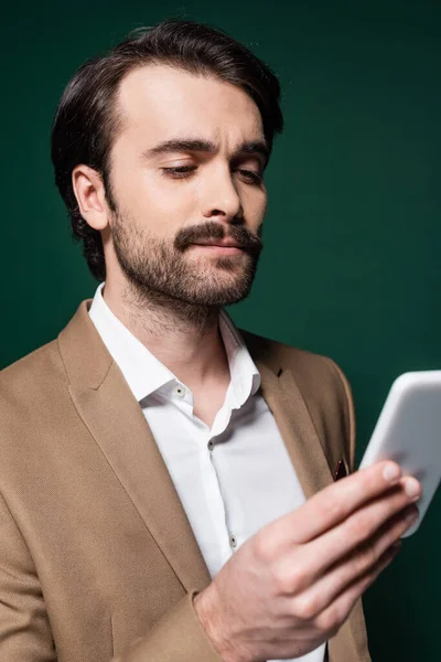Młody Człowiek Wąsami Patrząc Smartfona Ciemnozielonym — Zdjęcie stockowe