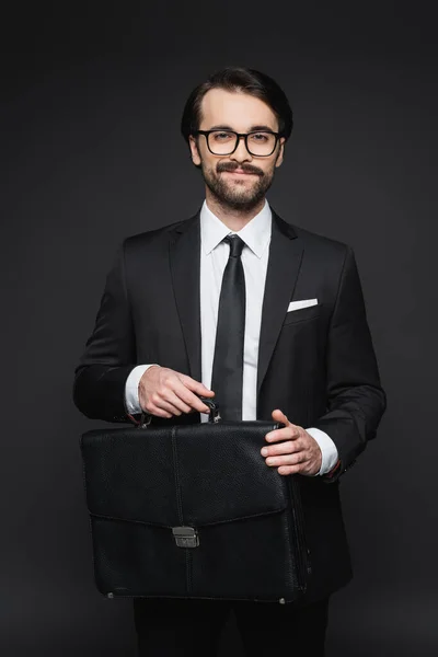 スーツ姿のビジネスマンが笑顔で黒い灰色の革のブリーフケースを持って — ストック写真