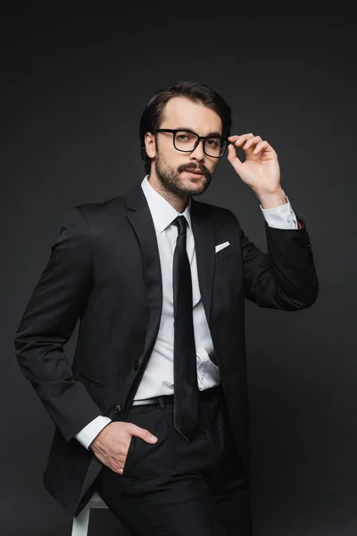 Hombre Negocios Ajustando Gafas Apoyándose Silla Mientras Posa Con Mano — Foto de Stock