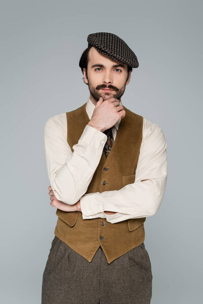 pensive man with mustache and retro clothing looking at camera isolated on grey