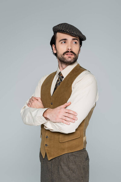 man with mustache and vintage style clothing standing with crossed arms isolated on grey