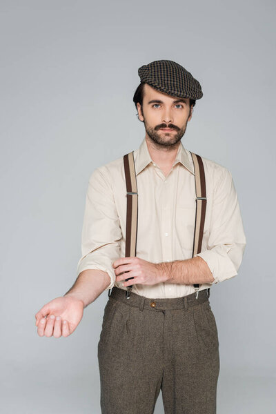 man in shirt with suspenders and retro style hat posing isolated on grey