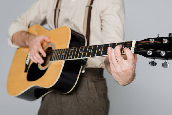 частичный взгляд на одежду человека в стиле ретро, играющую на акустической гитаре, изолированной на сером 