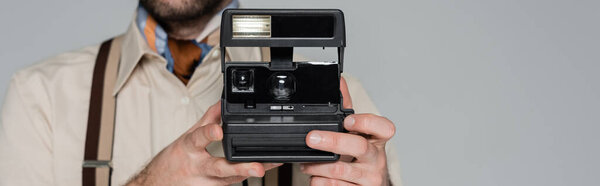 обрезанный вид человека в стиле ретро одежды и шляпы холдинг винтажная камера изолированы на сером, баннер