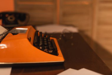 antique and orange typewriter machine near papers on desk clipart