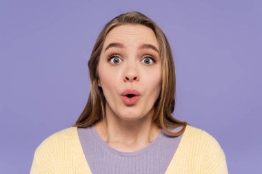 Şok olmuş genç bir kadın mor üzerine izole edilmiş kameraya bakıyor.