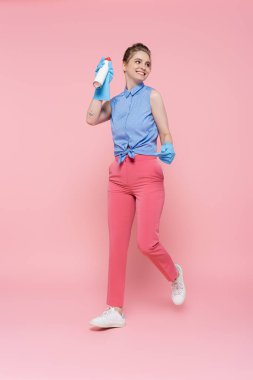 Lastik eldivenli, elinde pembe bir şişe parfüm tutan mutlu genç bir kadın. 