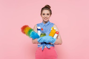 Plastik eldivenli, elinde deterjan ve toz fırçası olan pembe eldivenli genç bir kadın.