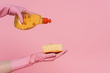 Pembeye izole edilmiş süngerin üzerine deterjan döken kadın görüntüsü. 