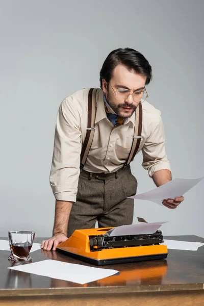 Periodista Anteojos Mirando Papel Cerca Máquina Escribir Escritorio Aislado Gris — Foto de Stock