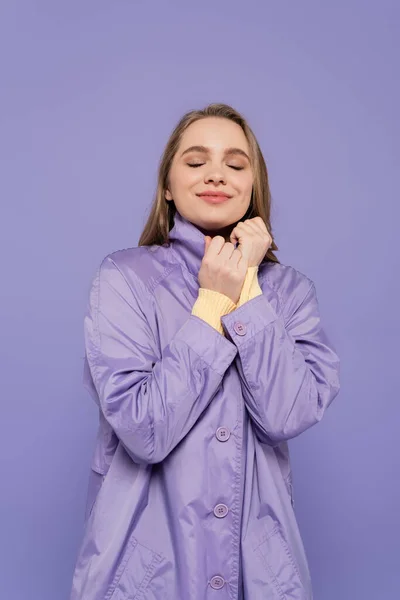 Mujer Joven Complacida Con Los Ojos Cerrados Gabardina Aislado Púrpura — Foto de Stock