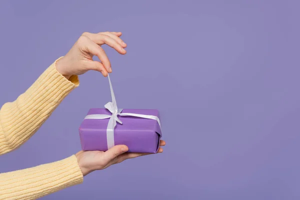 年轻女子在用紫色隔离的包装礼品盒上拉丝带的剪影 — 图库照片