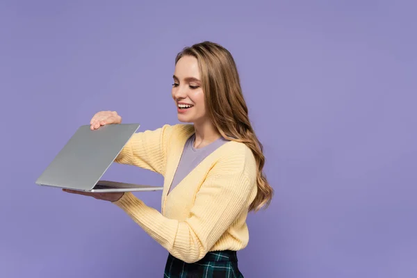 Uśmiechnięty Student Gospodarstwa Laptop Odizolowany Fioletowy — Zdjęcie stockowe