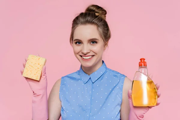 Joven Feliz Sosteniendo Esponja Botella Con Detergente Aislado Rosa — Foto de Stock
