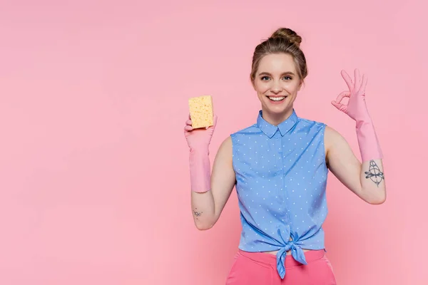 Glad Ung Kvinna Håller Svamp Och Visar Tecken Isolerad Rosa — Stockfoto