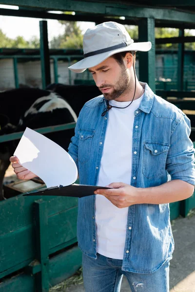 Jovem Agricultor Camisa Jeans Chapéu Aba Olhando Para Prancheta Perto — Fotografia de Stock