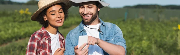 Fermier Tânăr Care Arată Smartphone Unui Coleg Afro American Vesel — Fotografie, imagine de stoc