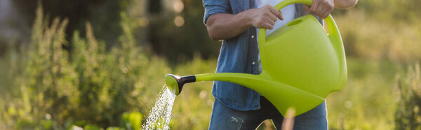cropped view of farmer watering garden on farm, banner