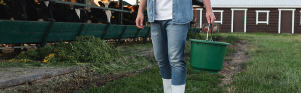 partial view of farmer with bucket near cowshed on farm, banner