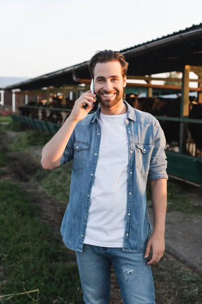 Agricultor Falando Smartphone Perto Cowhouse Borrado Sorrindo Para Câmera — Fotografia de Stock