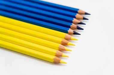Beyaz arkaplanda sarı ve mavi renkli kalemlerin görüntüsünü kapat 