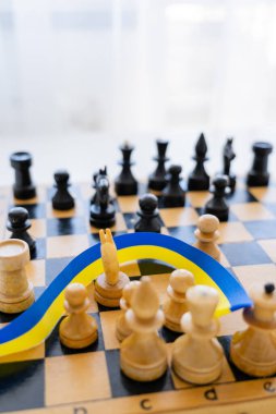 Beyaz arkaplanda bulanık satranç tahtasında mavi ve sarı kurdele 