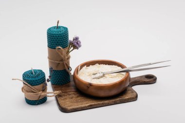 Kuru çiçekli mumlar, balmumunun yanında gri arka plandaki ahşap kasede.