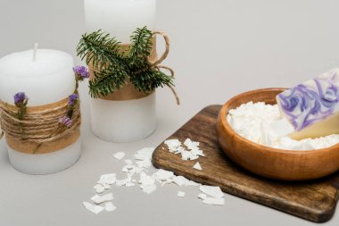 Kuru balmumunun yanındaki bitkilerin olduğu el yapımı mumlar gri arka planda tahta tahtada.