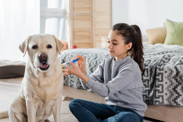 Brünettes Mädchen Spritzt Labrador Hund Mit Spielzeugspritze — Stockfoto