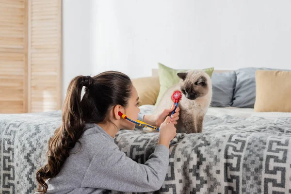 Preteen Dívka Vyšetření Kočka Hračkou Stetoskop Při Hraní Doma — Stock fotografie