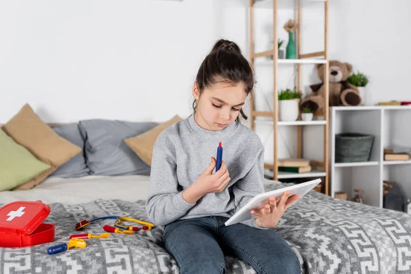 Mädchen Mit Spielzeugspritze Schaut Schlafzimmer Auf Digitales Tablet — Stockfoto