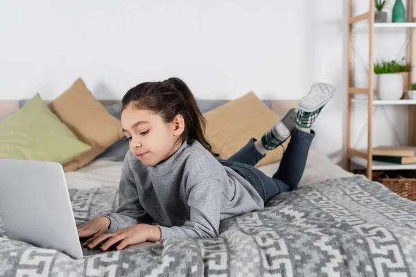 少女躺在床上 在笔记本电脑上打字的全景 — 图库照片