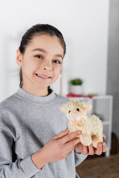 Leende Flicka Som Visar Leksak Lamm Och Tittar Kameran — Stockfoto