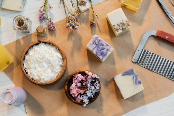 テーブルの上のクラフト紙の上の花やバーの近くの石鹸フレークのトップビュー — ストック写真
